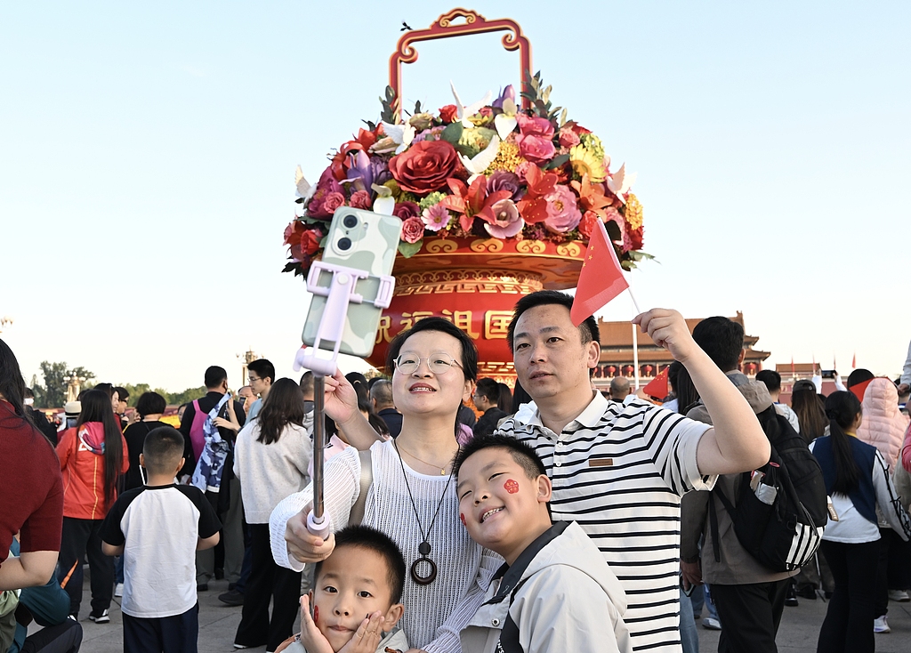 A group takes a selfie with this year's large flower basket on Tiananmen Square in Beijing during the flag-raising ceremony held on October 1, 2025 to mark the 76th anniversary of the founding of the People's Republic of China. /VCG