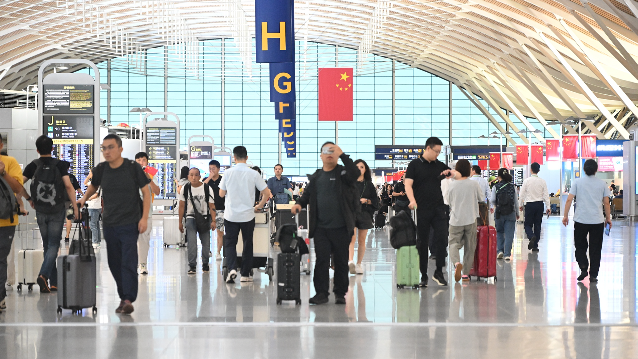 Bright national flags hang high as Shanghai Pudong International Airport sees a peak in inbound and outbound passenger traffic at border checkpoints, Shanghai, China, September 30, 2025. /VCG