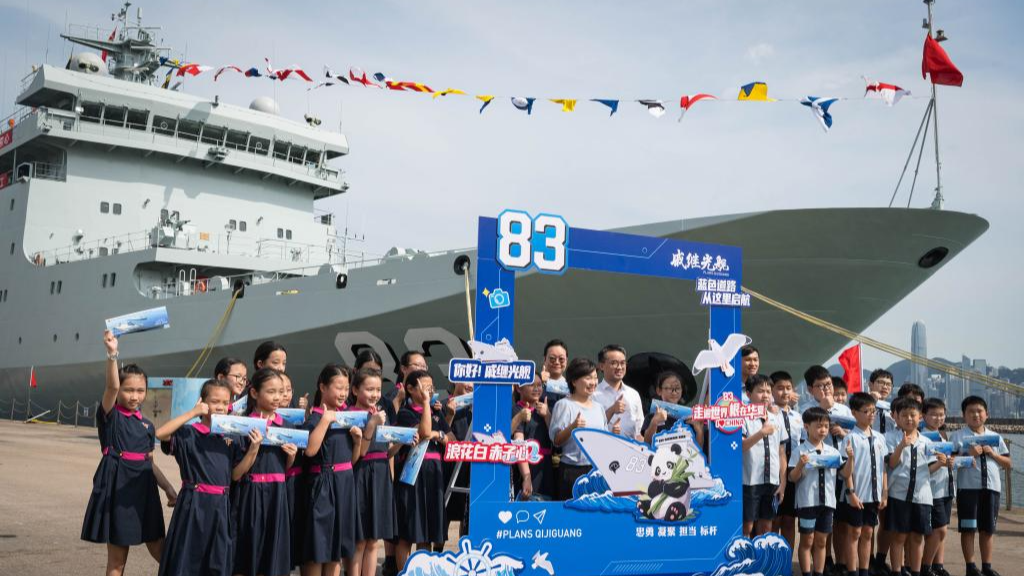 Students and residents take a group photo in front of the PLA Navy ship Qi Jiguang in south China's Hong Kong, September 30, 2025. /Xinhua
