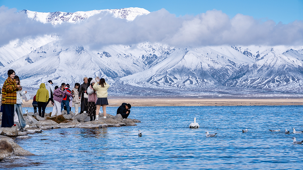 Visitors enjoy the scenery from a shore of Sayram Lake located in the northern Tianshan Mountains in the Bortala Mongolian Autonomous Prefecture in Xinjiang, October 3, 2025. /VCG