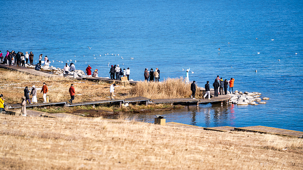 Visitors enjoy the scenery from a shore of Sayram Lake located in the northern Tianshan Mountains in the Bortala Mongolian Autonomous Prefecture in Xinjiang, October 3, 2025. /VCG