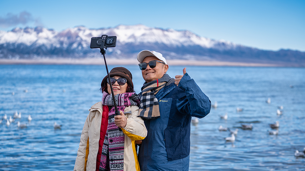 Visitors enjoy the scenery from a shore of Sayram Lake located in the northern Tianshan Mountains in the Bortala Mongolian Autonomous Prefecture in Xinjiang, October 3, 2025. /VCG