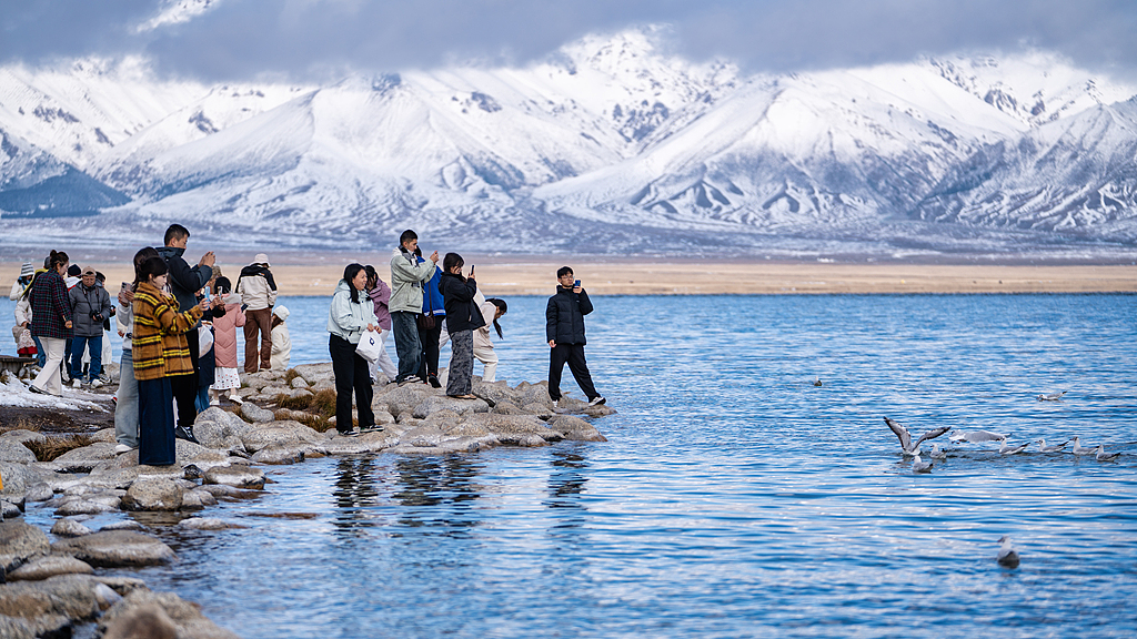 Visitors enjoy the scenery from a shore of Sayram Lake located in the northern Tianshan Mountains in the Bortala Mongolian Autonomous Prefecture in Xinjiang, October 3, 2025. /VCG