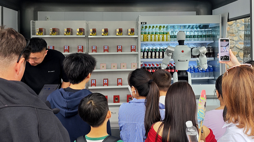 People take pictures when a humanoid robot is serving beverages in Beijing, China, October 1, 2025. /VCG