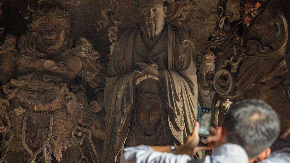 A tourist takes pictures of sculptures in Tiefo Temple, Shanxi, China, October 3, 2025. /VCG