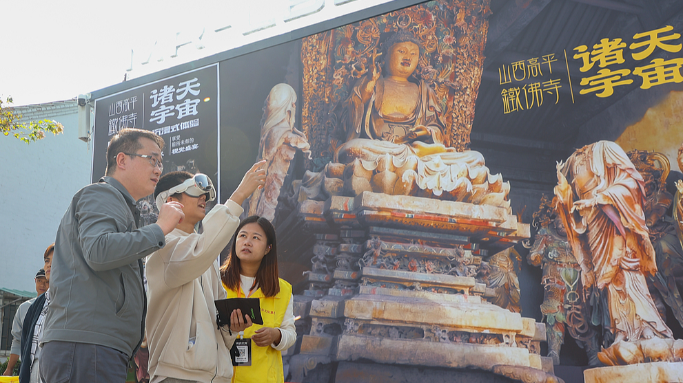 A staffer introduces the MR experience to tourists at Tiefo Temple, Shanxi, China, October 3, 2025. /VCG