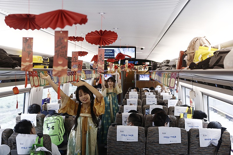 Two train attendants dressed in Hanfu, the traditional clothing of the Han ethnic group in China, perform a dance for passengers on the G99 train, October 3, 2025. /VCG