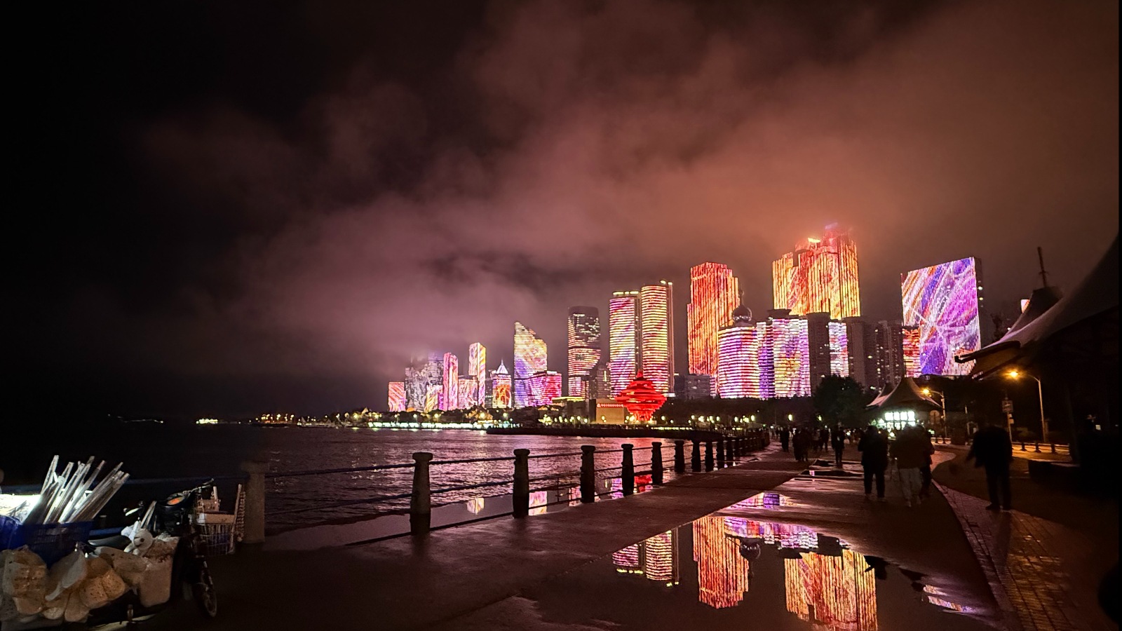 Rainwater pools reflecting Qingdao's illuminated skyline, creating a mirrored cyberpunk effect, September 2025, Qingdao, China /Zaruhi Poghosyan
