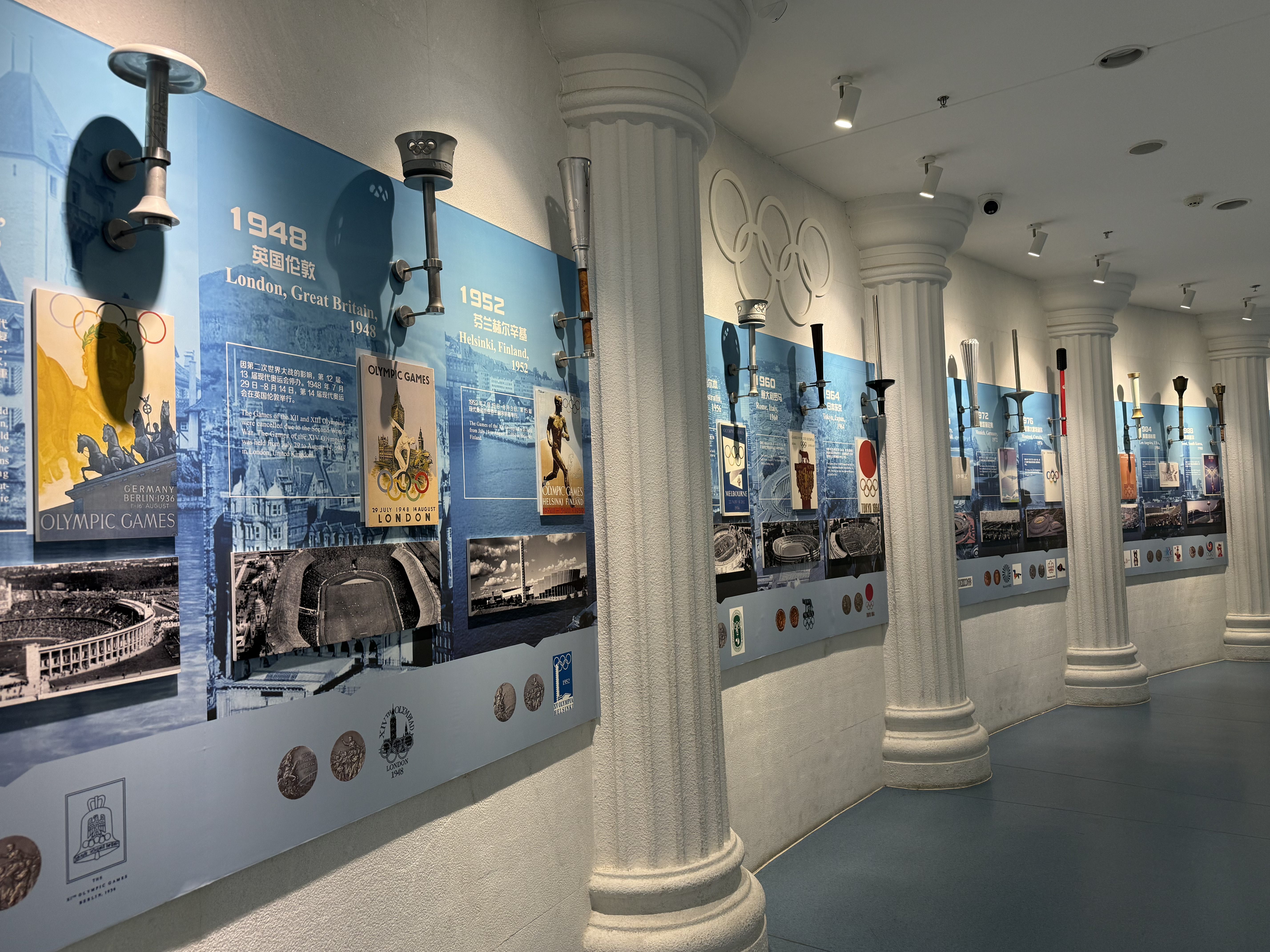 Olympic torches from different years displayed in sequence on a glowing wall, September 2025, Qingdao, China /Zaruhi Poghosyan