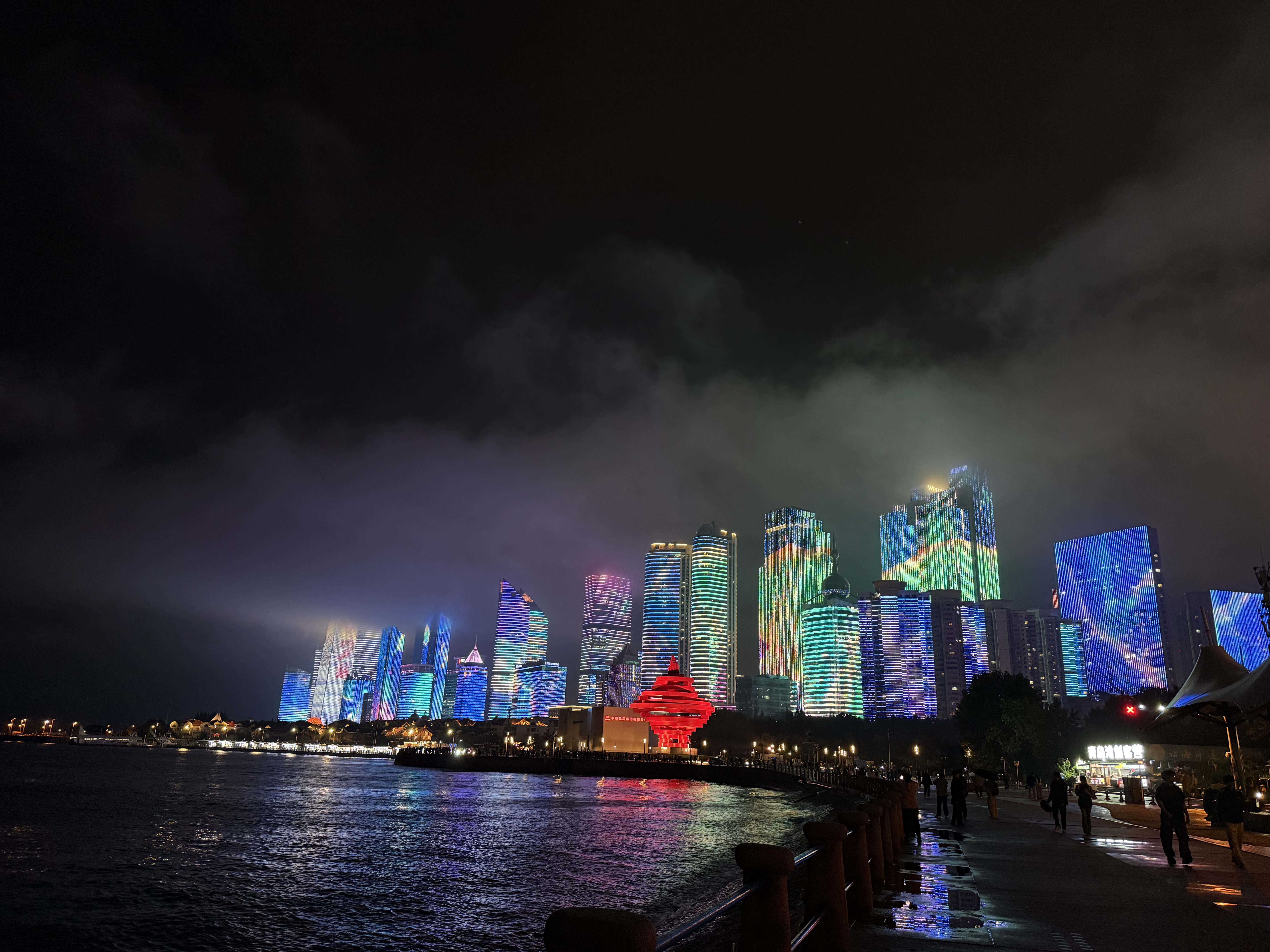 Rainwater pools and the sea reflecting Qingdao's illuminated skyline, September 2025, Qingdao, China /Zaruhi Poghosyan