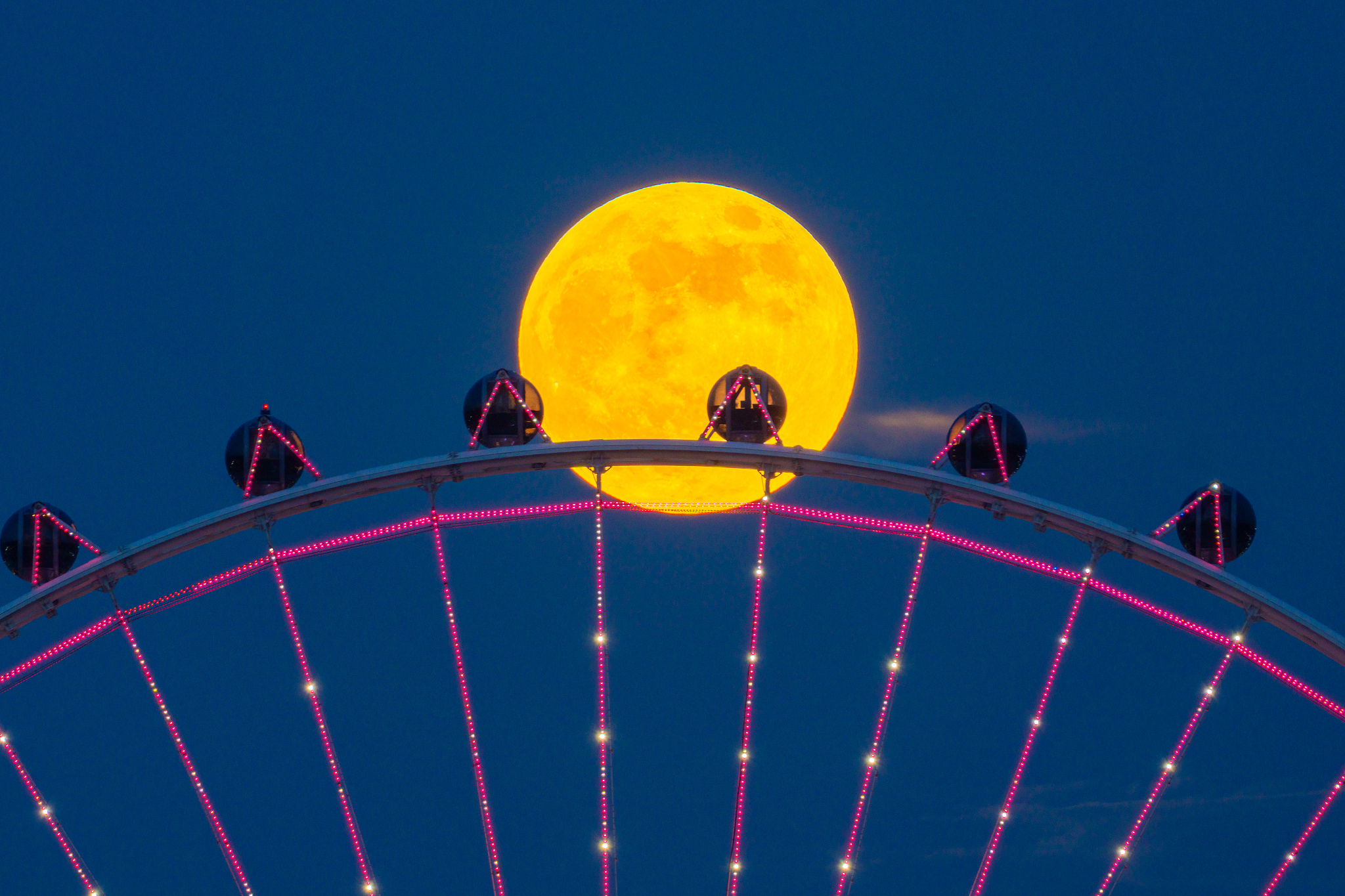 A supermoon is pictured over a ferris wheel in Shunde, Guangdong Province. /VCG