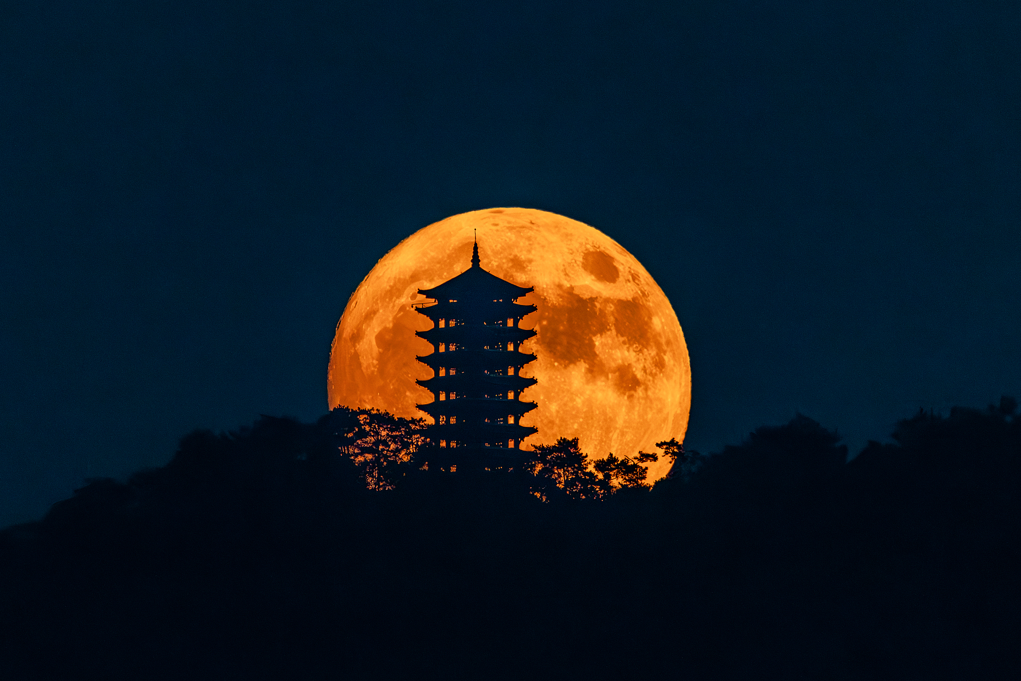 A supermoon forms a silhouette against the Jinyun Tower in southwest China's Chongqing Municipality. /VCG