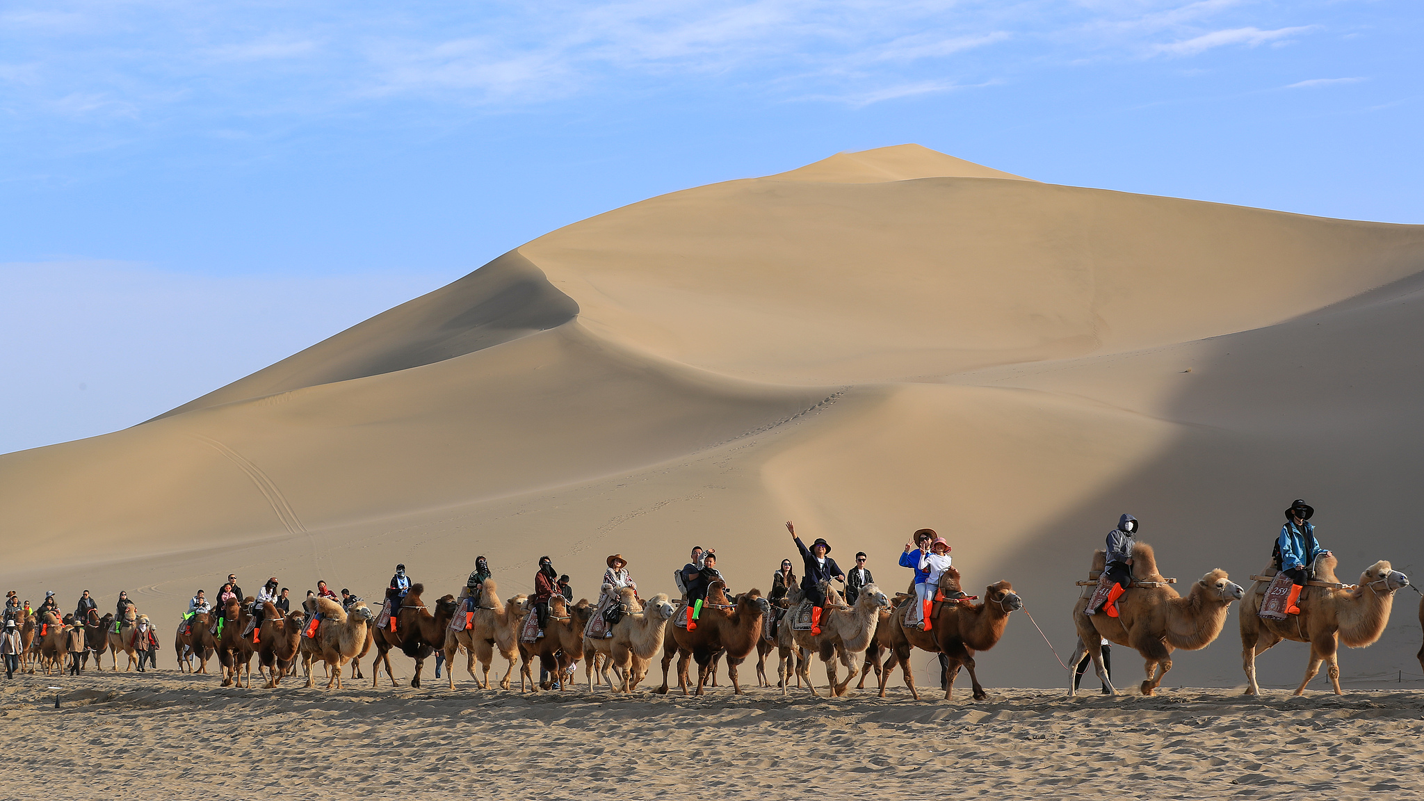 People enjoy the desert views from camels at the Mingsha Mountain and Crescent Spring scenic spot in Dunhuang, northwest China's Gansu Province on October 6, 2025. /VCG