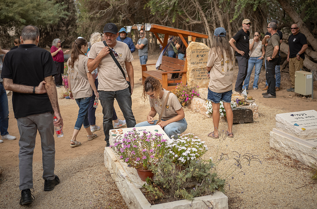 A woman sits next to a grave at the Kibbutz Nir Oz cemetery during a ceremony commemorating the two-year anniversary of the attack, Nir Oz, Israel, October 6, 2025. /VCG