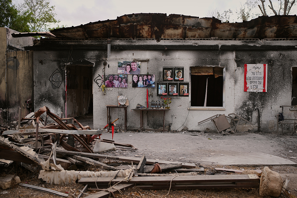 Photos of the Siman Tov family are plastered on their burnt house where all five of them were killed during the Hamas attack on October 7, 2023, Nir Oz, Israel. /VCG 