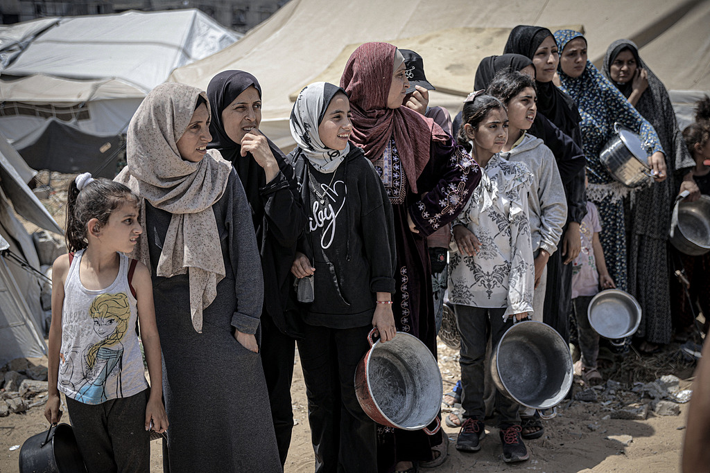 Palestinian women and children living in tents receive food distributed by aid organizations in Al Mawasi district of Khan Younis, Gaza, May 30, 2025. /VCG