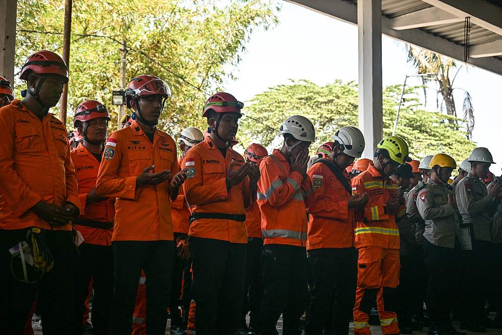 Rescue team members from the National Search and Rescue Agency and police pray during a ceremony marking the end of debris removal and search operations at the site of the collapsed Al Khoziny Islamic boarding school in Sidoarjo, East Java, October 7, 2025. /CFP
