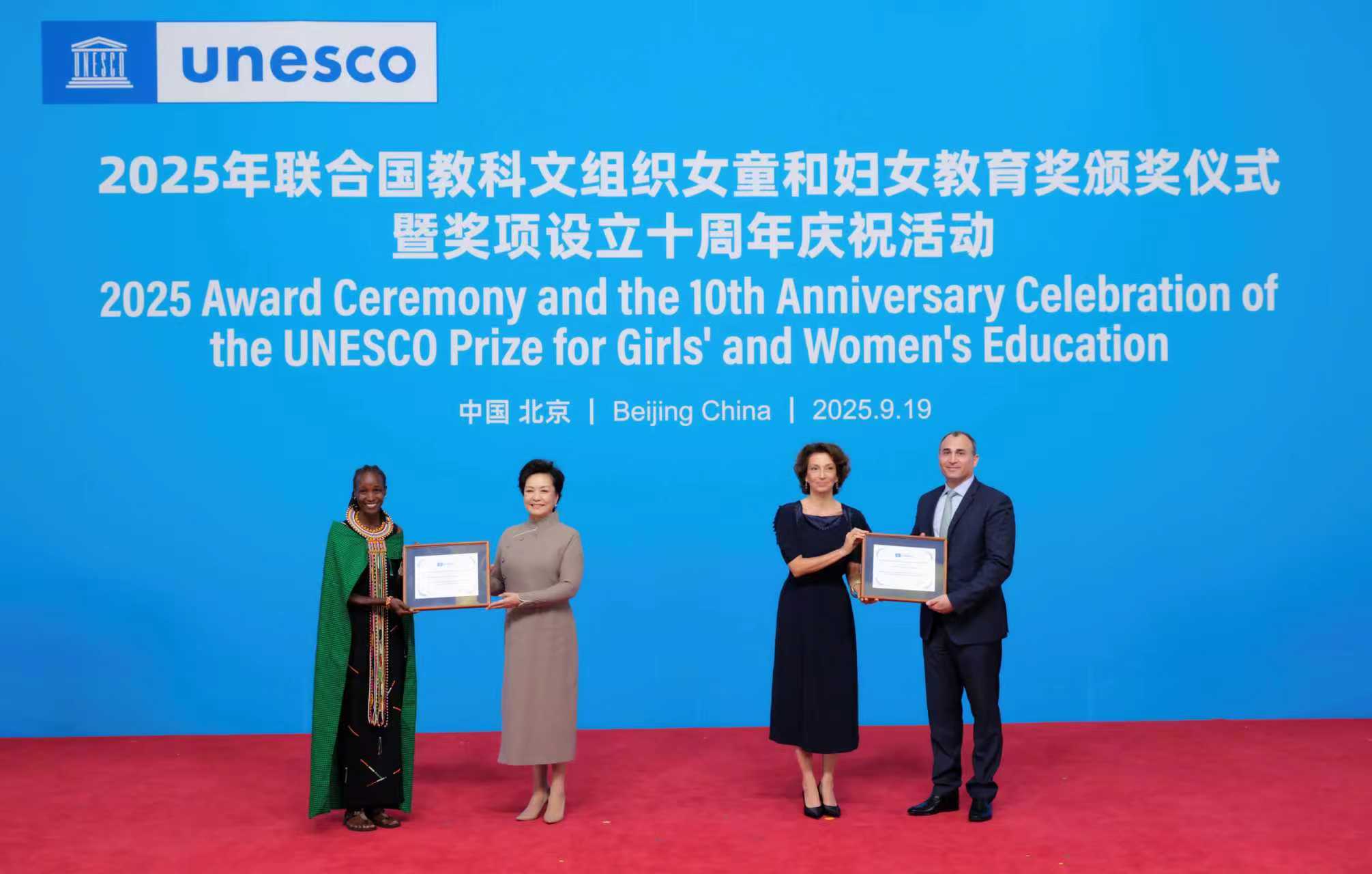 Peng Liyuan, wife of Chinese President Xi Jinping and a special envoy of the United Nations Educational, Scientific and Cultural Organization (UNESCO) for the advancement of girls' and women's education, and Audrey Azoulay, director-general of the UNESCO, present awards to representatives of award-winning projects from Kenya and Lebanon at the 2025 UNESCO Prize for Girls' and Women's Education award ceremony in Beijing, capital of China, September 19, 2025. /Xinhua