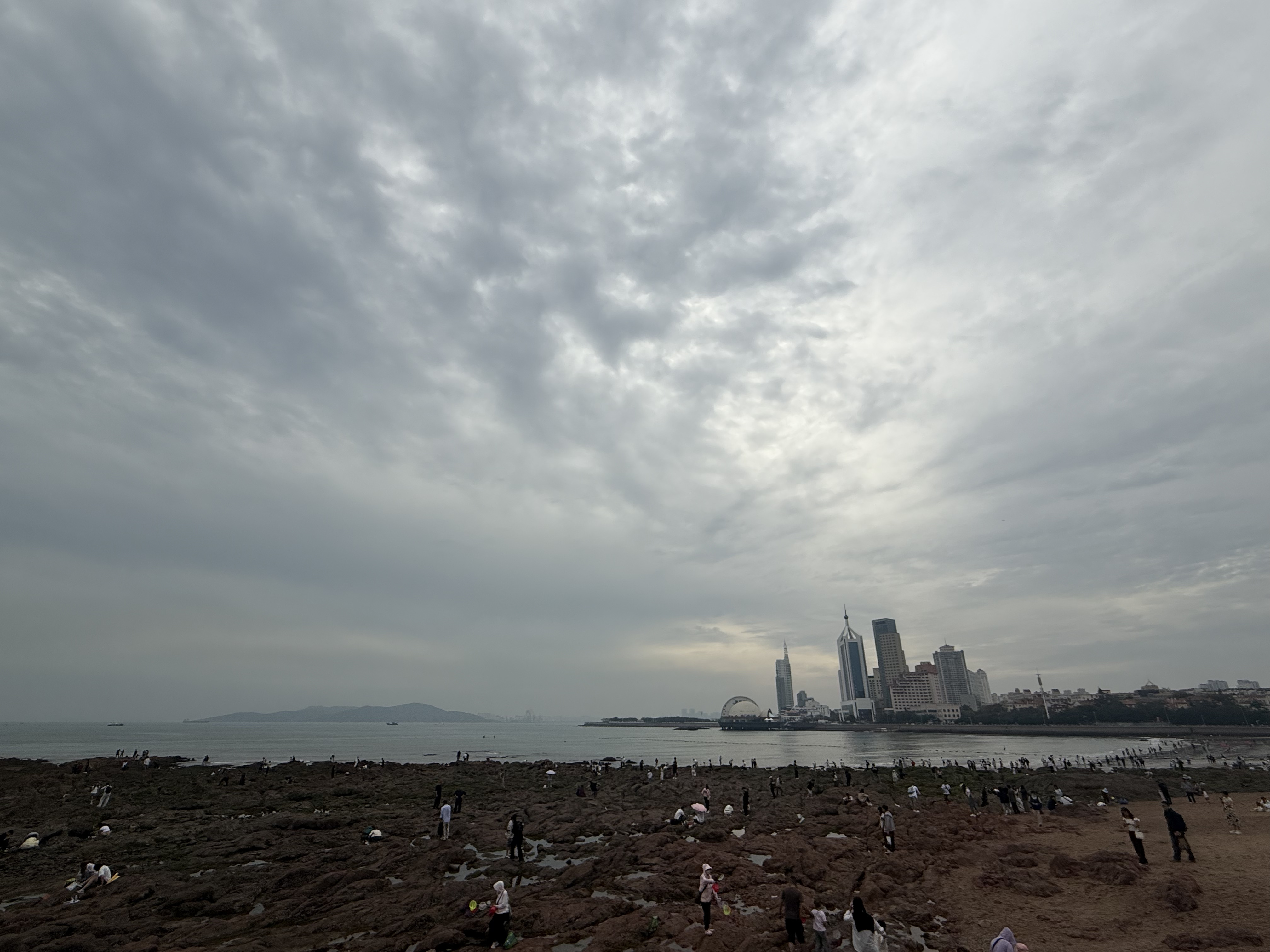Visitors and locals explore the tidal flats by Zhanqiao Pier, with Qingdao's skyline rising in the background, Shandong Province, China, September 2025. Zaruhi Poghosyan /CGTN