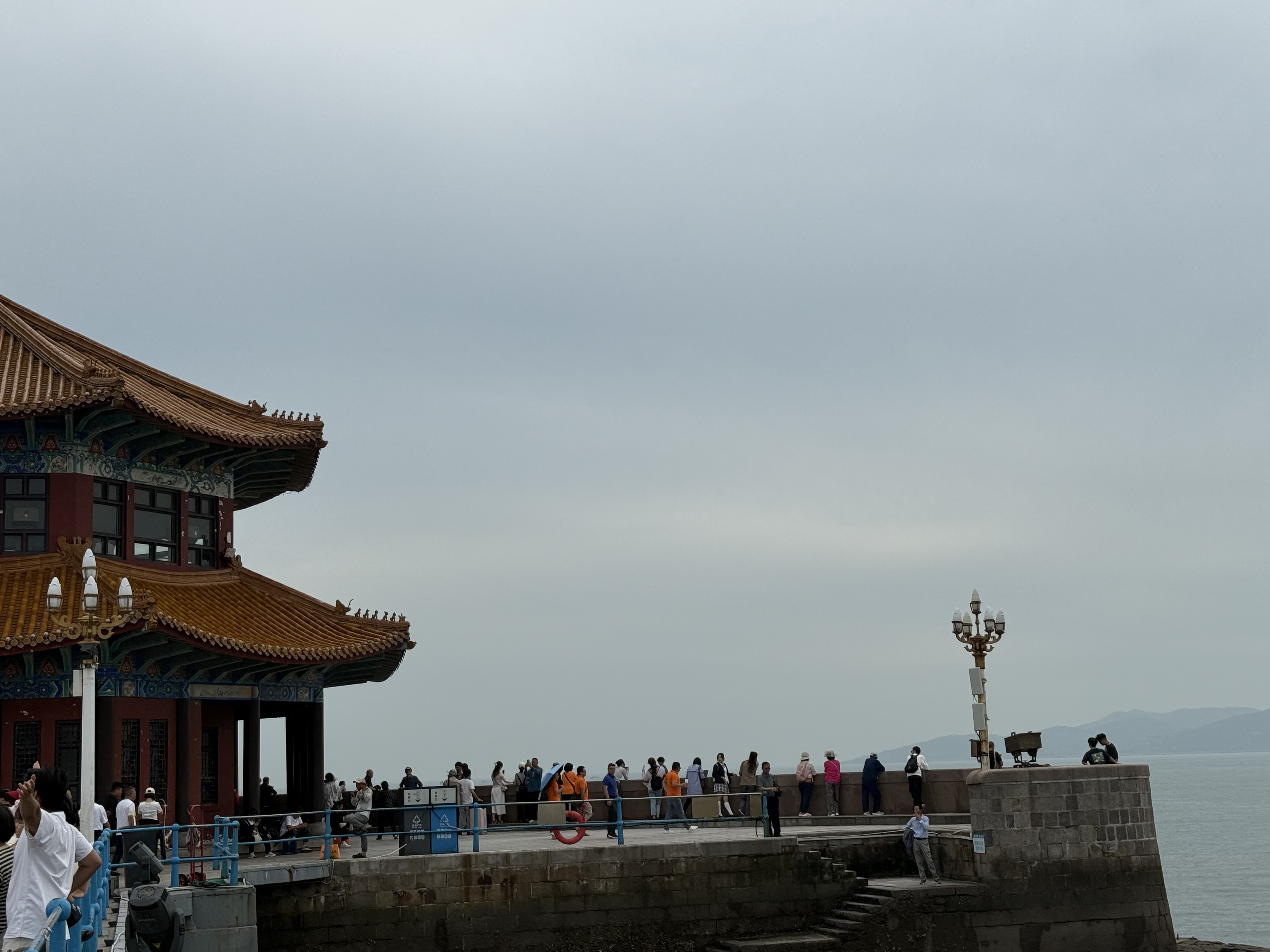 Visitors gather near the stone railing of Huilan Pavilion, taking in the view across Qingdao Bay, Shandong Province, China, September 2025. Zaruhi Poghosyan /CGTN