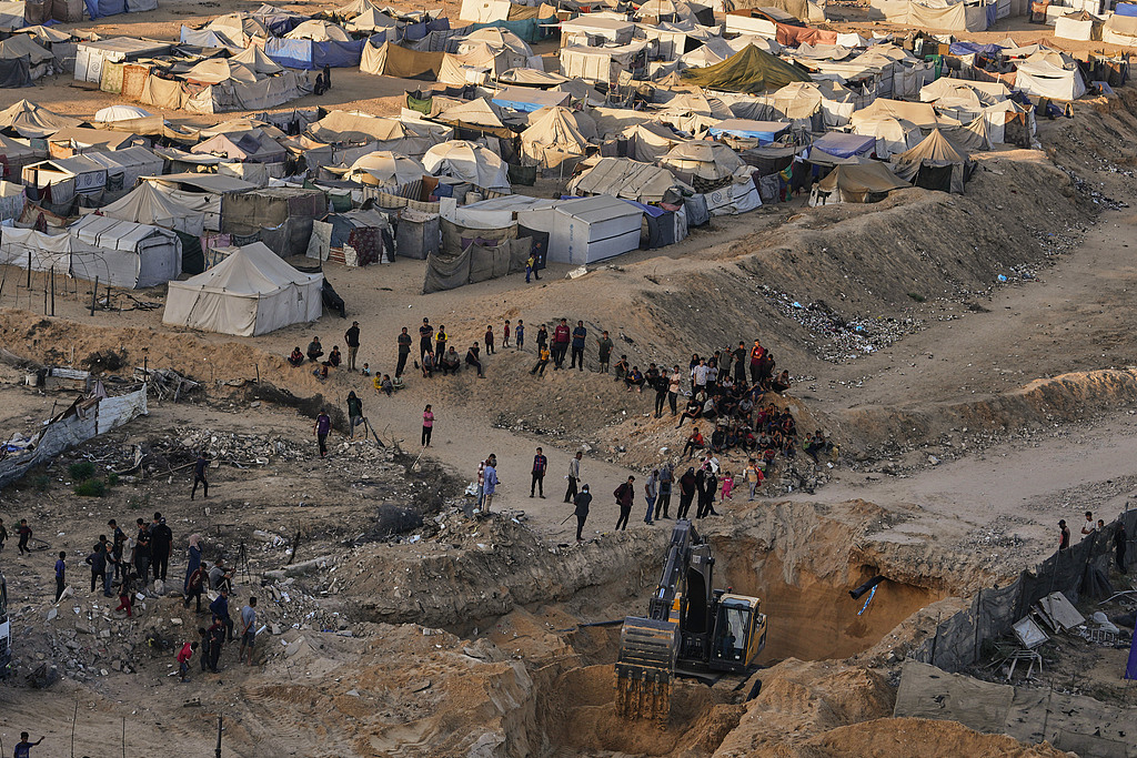 Palestinians watch machinery and some workers from Egypt searching for the bodies of Israeli hostages at Hamad City, Khan Younis, southern Gaza Strip, October 27, 2025. /VCG