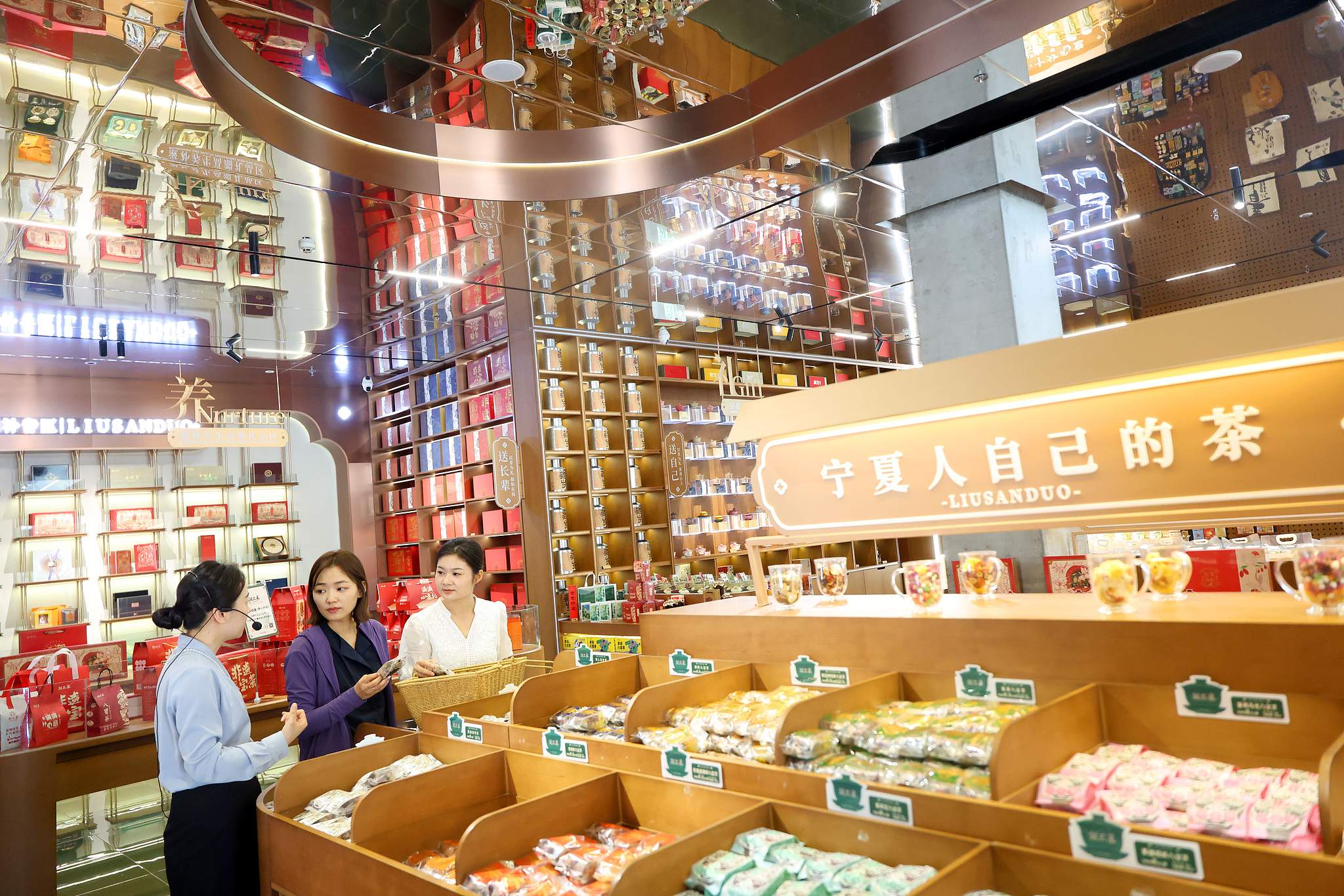 A photo taken in July 2025 shows visitors exploring the local tradition of Eight Treasures Tea – a beverage made from tea leaves, rock sugar, longan, raisins, red dates, chrysanthemum, sesame, and goji berries – at an intangible cultural heritage experience center in Wuzhong, Ningxia Hui Autonomous Region. /VCG