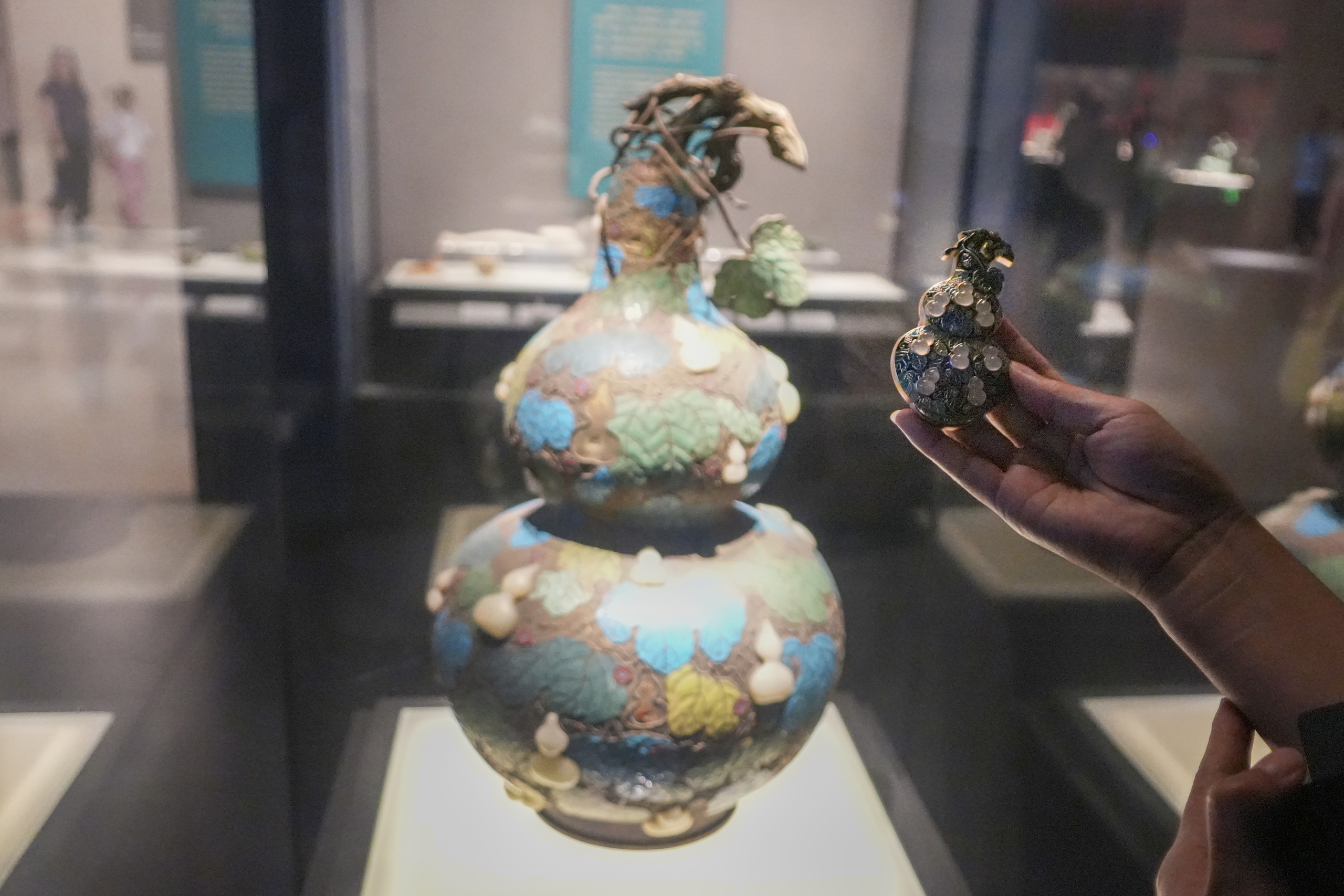 A visitor compares a gourd fridge magnet to the original on display at the Henan Museum in Zhengzhou, Henan Province. /IC