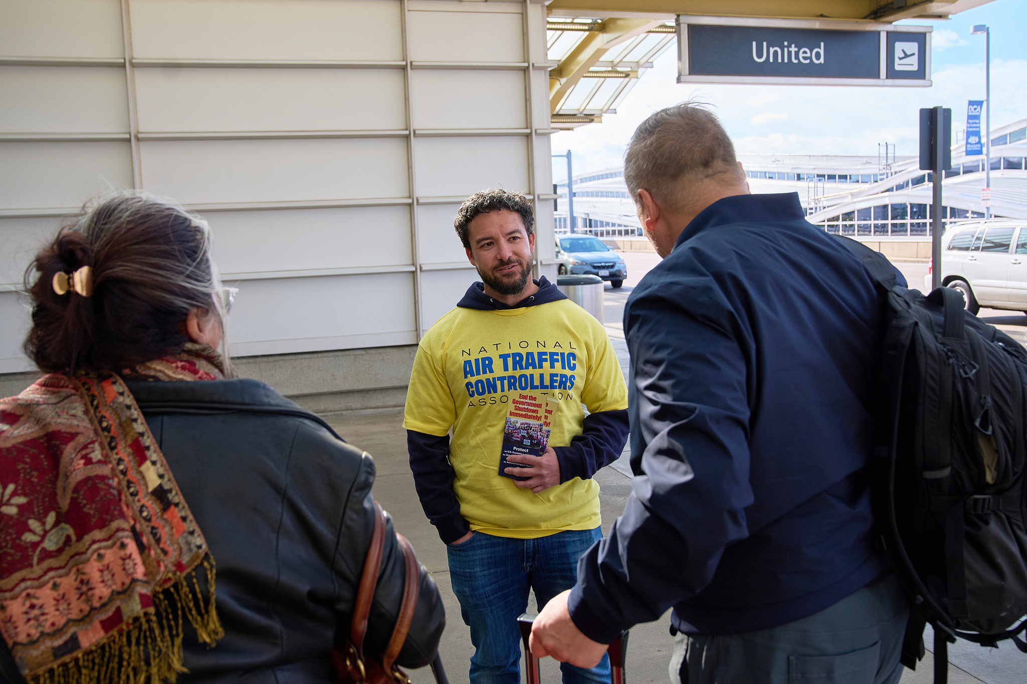 Air traffic controller hands out pamphlets about the government shutdown, including how he is working without pay, in Arlington, October 28, 2025. /VCG
