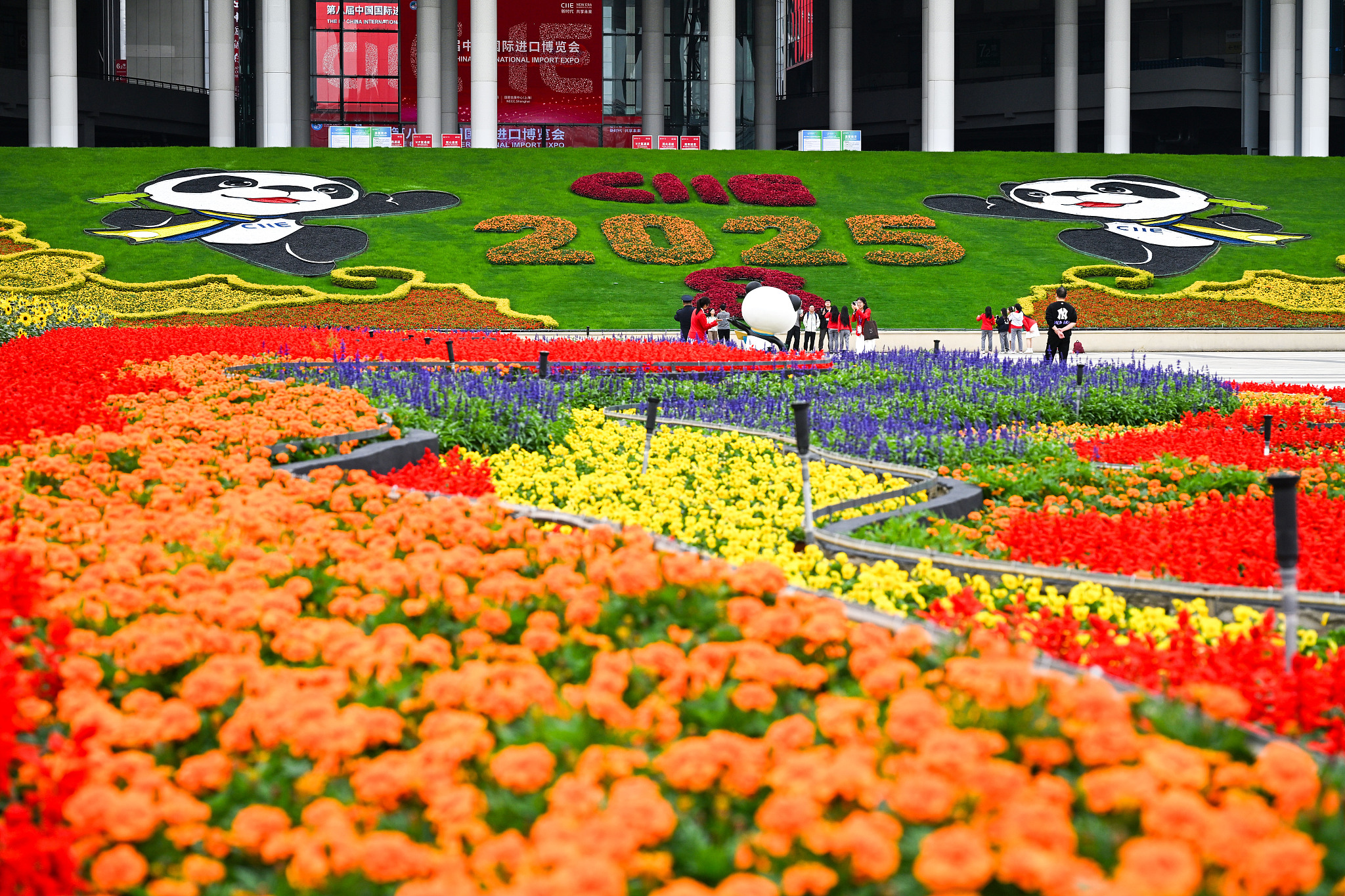 Flags flutter and flowers bloom at the South Square of the National Exhibition and Convention Center (Shanghai) on the eve of the 8th China International Import Expo, Shanghai, China, November 4, 2025. /VCG