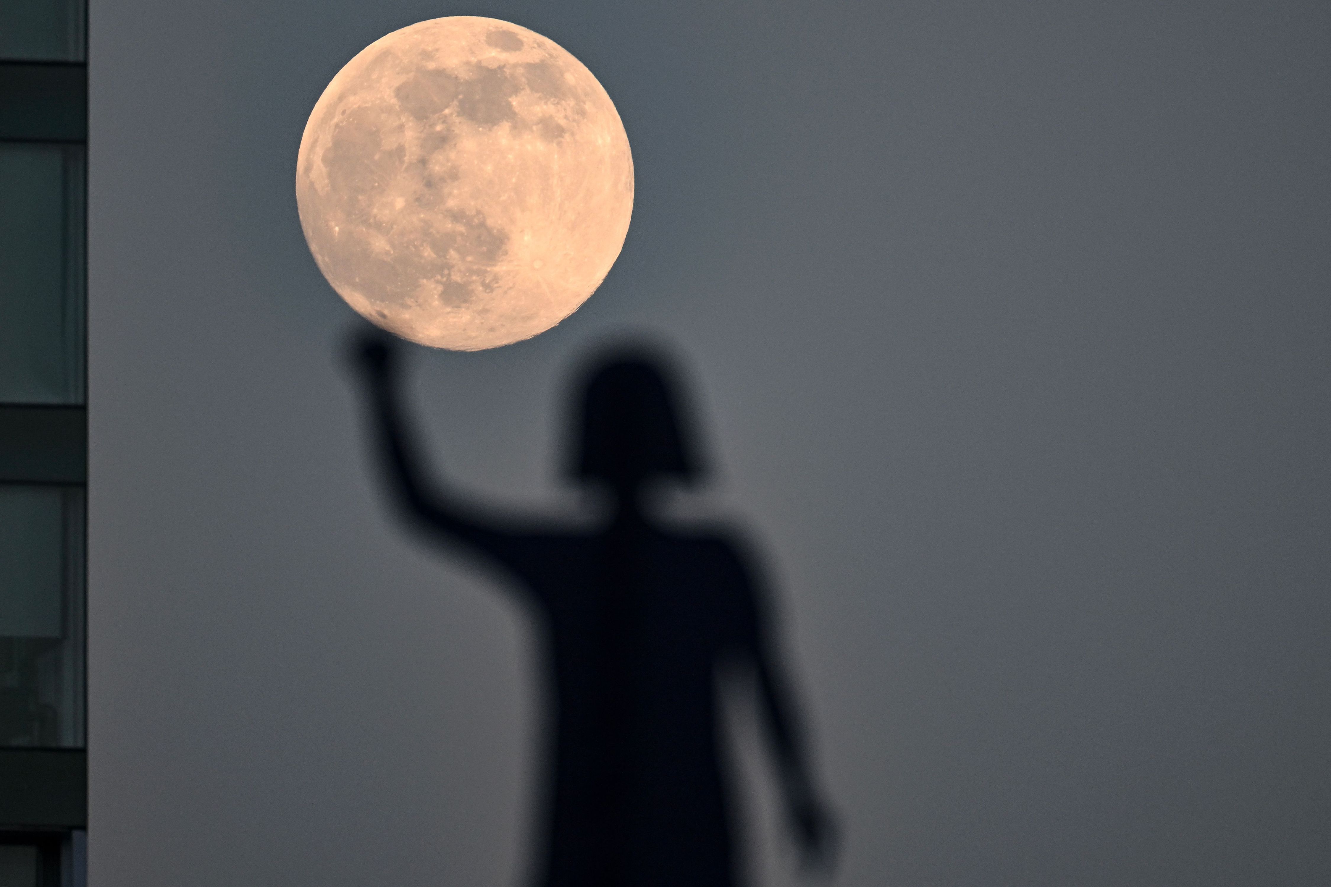The supermoon is seen behind the statue dedicated to 