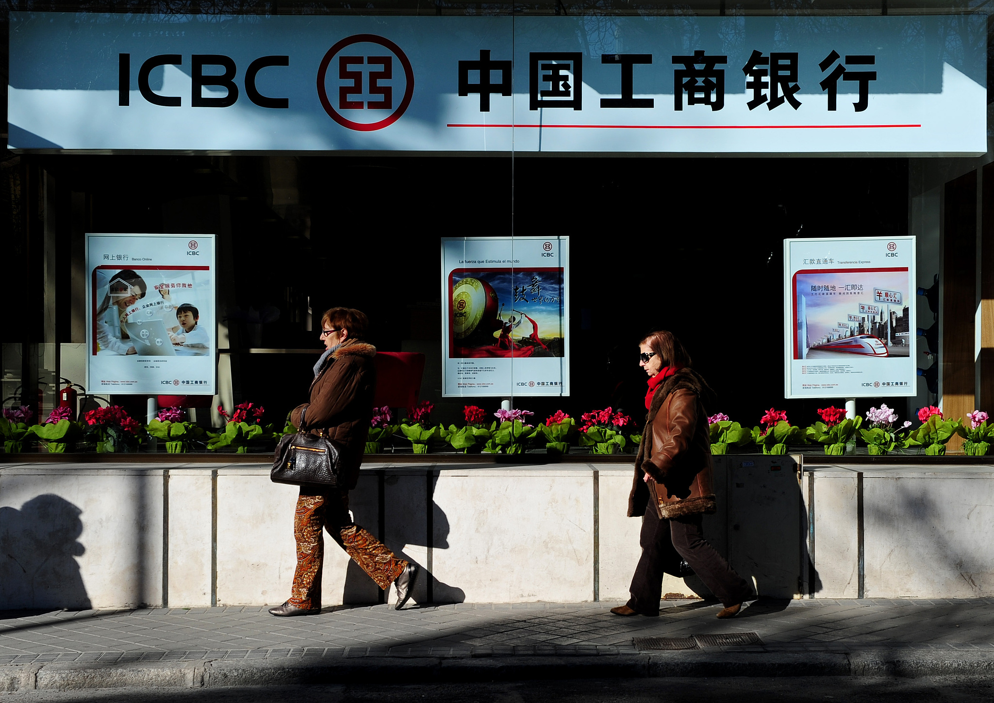 Two women stroll by a newly opened branch of the Industrial and Commercial Bank of China in Madrid, Spain, January 24, 2011. /VCG