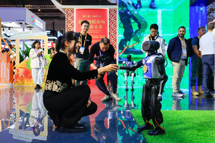 An exhibitor shakes hands with a robot at the China Pavilion during the eighth China International Import Expo, November 5, 2025. /Xinhua