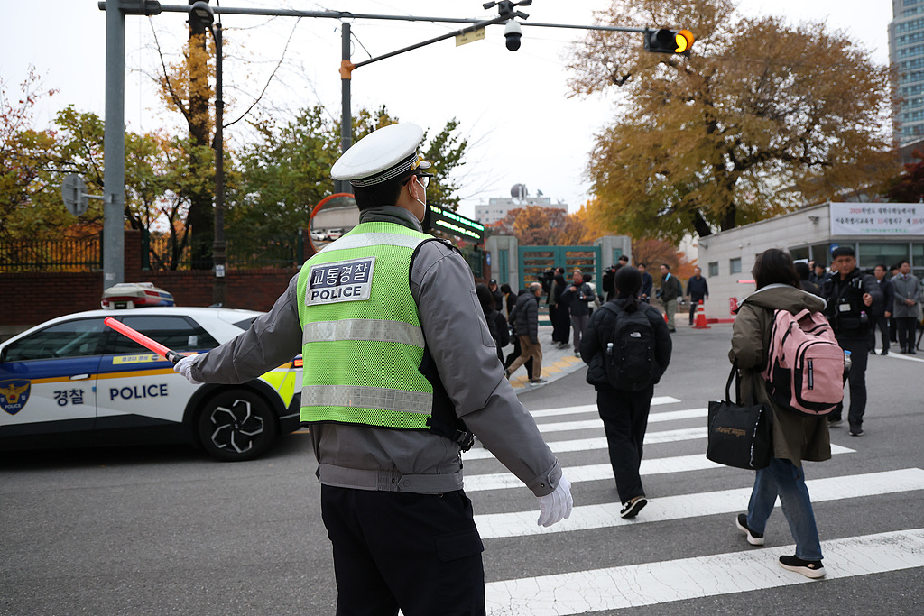A police officer helps students get to their College Scholastic Ability Test center in front of the main gate of an examination school in Seoul, South Korea, November 13, 2025. /CFP