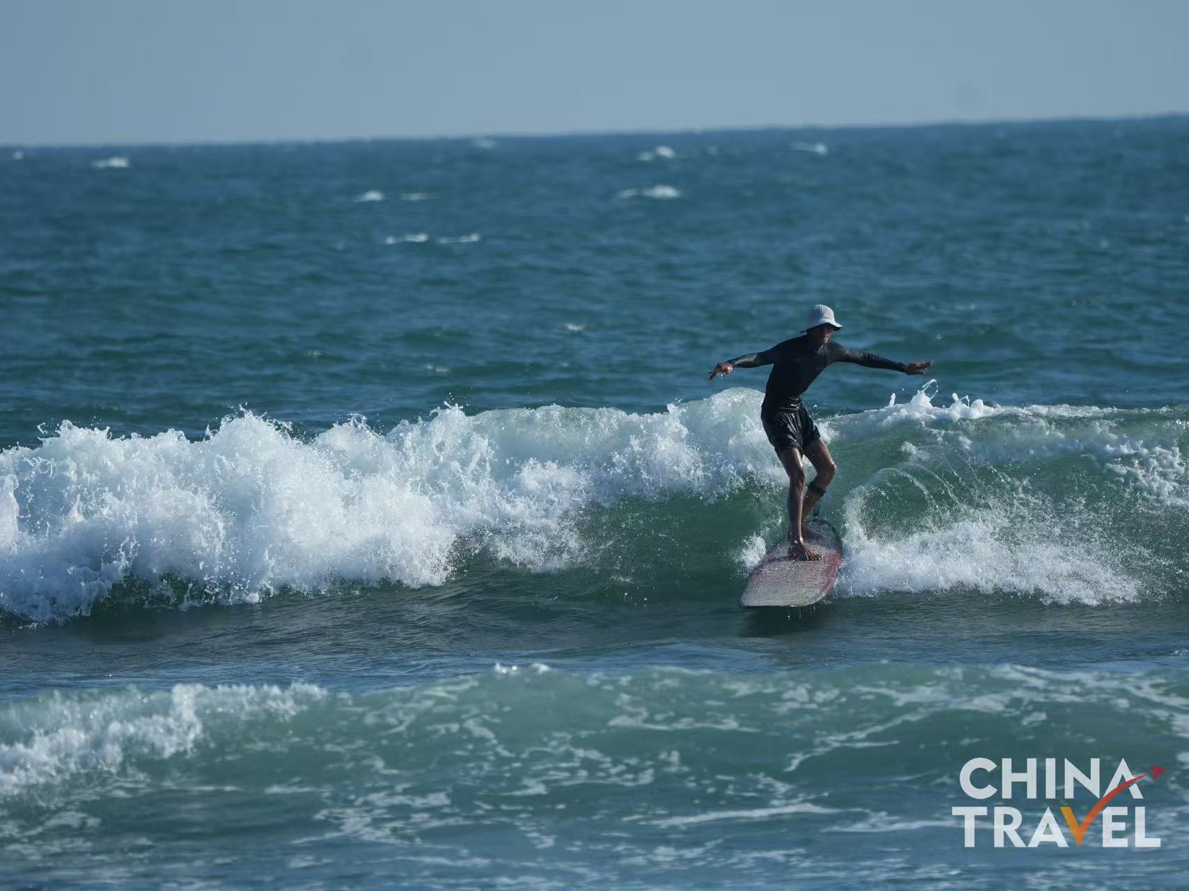 Surfers are seen at Riyue Bay in Wanning, Hainan. /CGTN

