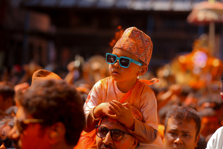 A Nepali child, soaked in vermillion powder, sits on the shoulder of his parent while observing the annual Sindoor Jatra festival in Thimi, Nepal, April 15, 2025. /CFP
