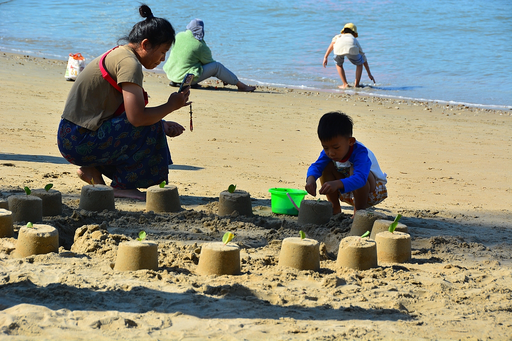 Seorang ibu dan anaknya menikmati membangun istana pasir di pantai Teluk Sanya, Provinsi Hainan, Tiongkok selatan, 22 November 2025. /VCG
