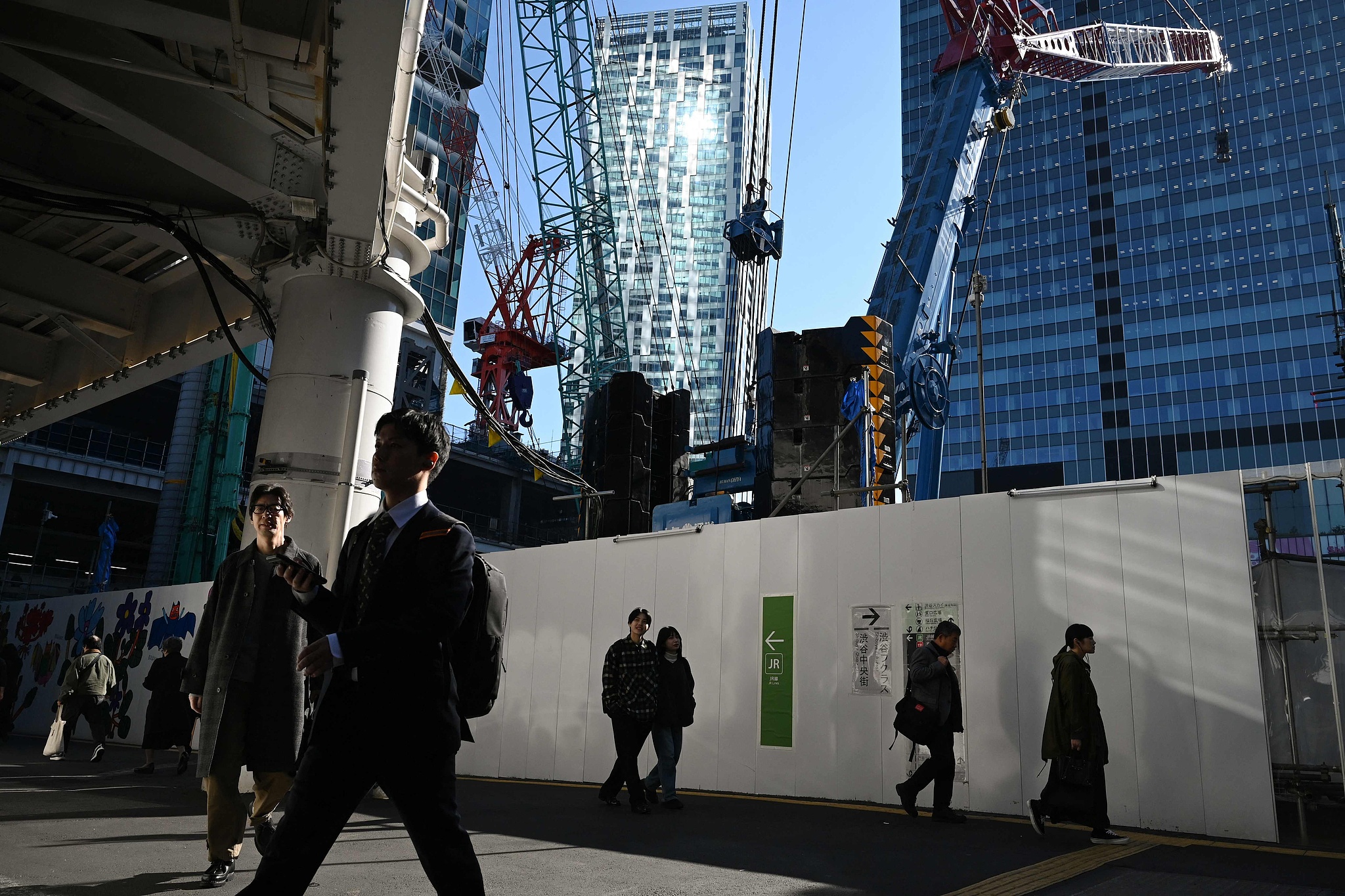 People walk next to a construction site at the Shibuya district in Tokyo, Japan, November 21, 2025. /VCG
