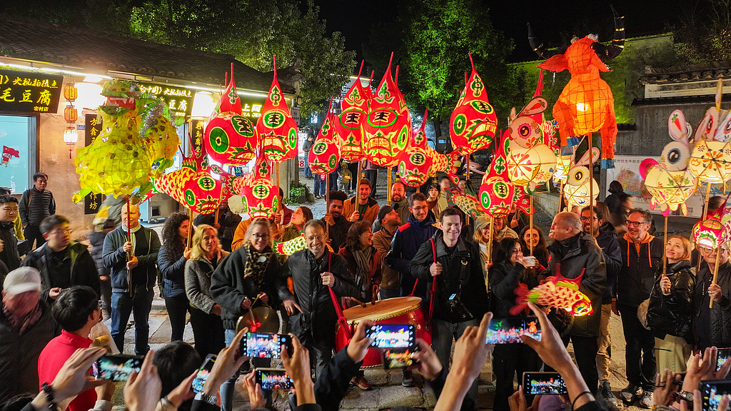 International visitors join a fish lantern performance, an intangible cultural heritage activity, in Hongcun Scenic Area in Yixian County of Huangshan, Anhui on November 15, 2025. /VCG