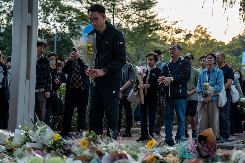A man lays flowers near the scene where a major fire engulfed several residential buildings at Wang Fuk Court in Tai Po area, Hong Kong Special Administrative Region, November 29, 2025. /VCG