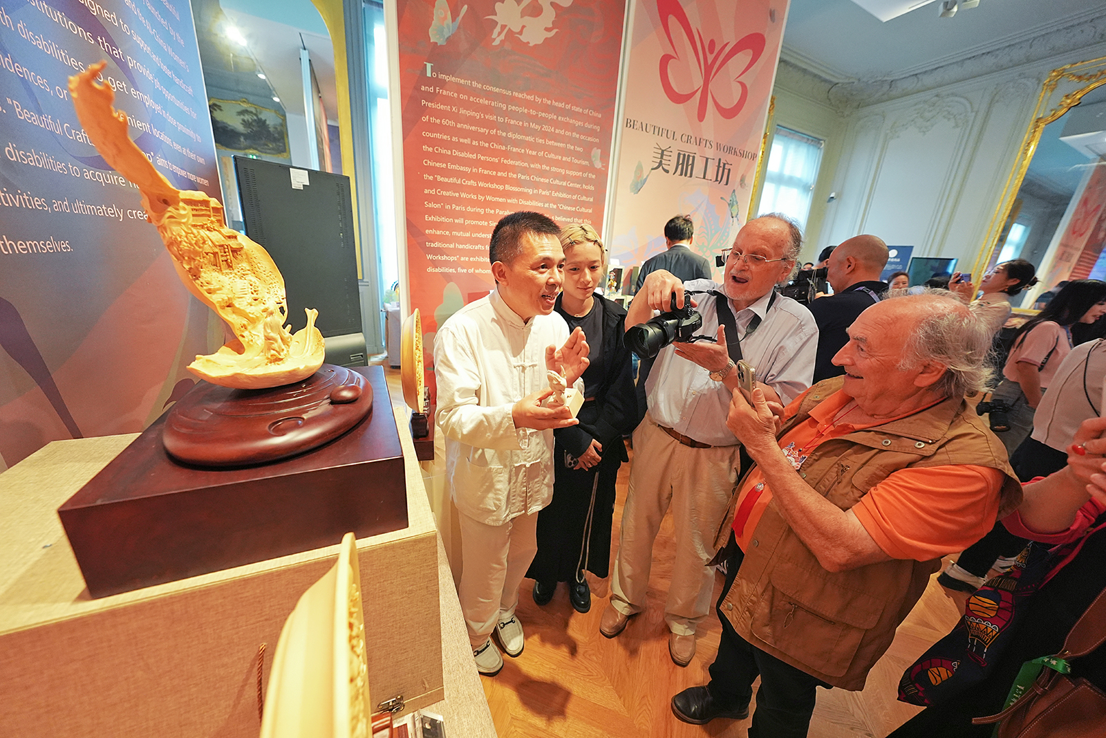 Visitors take photos at an exhibition featuring Chinese cultural and creative products made by disabled Chinese women at the China Culture Center in Paris, France on September 3, 2024. /Zhejiang Daily via IC