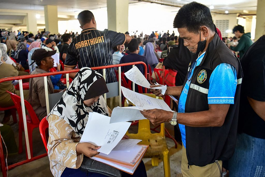 An official checks the paperwork of a flood victim as people register to receive disaster relief funds in Narathiwat City Hall, Narathiwat Province, Thailand, December 3, 2025. /CFP