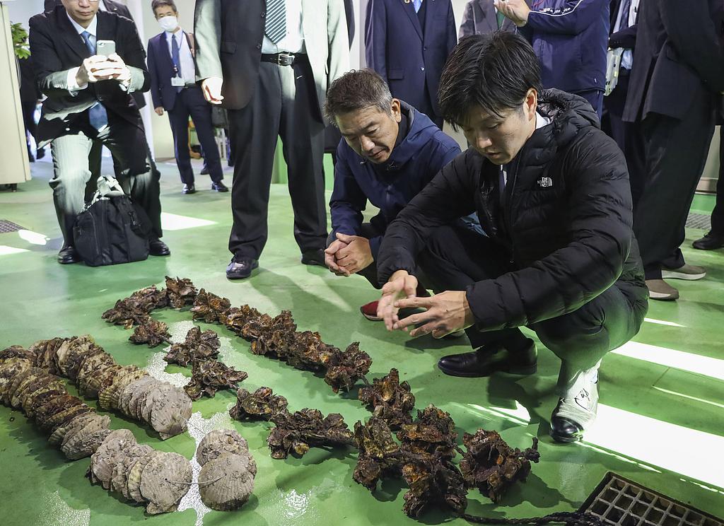 Japanese Agriculture, Forestry and Fisheries Minister Norikazu Suzuki (right) listens to a briefing from an oyster farmer following reports of mass oyster deaths at many oyster farms in Higashihiroshima City, Hiroshima Prefecture, Japan, November 19, 2025. /CFP
