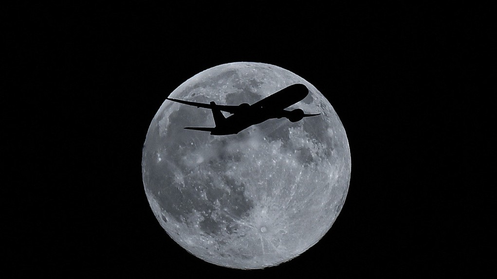 Silhouette of a plane in front of full moon in the sky in London, United Kingdom, December 4, 2025. /VCG