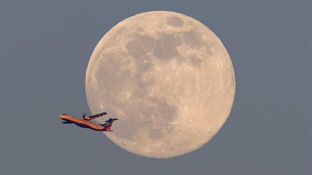 An airplane flies as the supermoon shines over the sky in Kathmandu, Nepal, December 4, 2025. /VCG