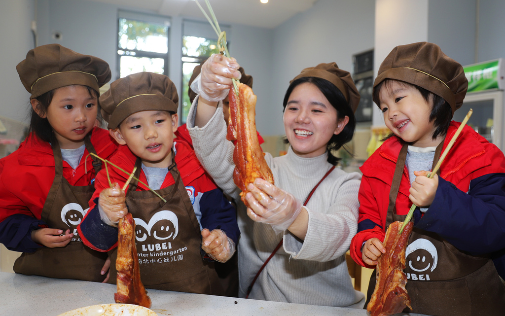 Children learn how to cure preserved pork at a kindergarten in Taizhou City, Jiangsu Province to mark the solar term of Major Snow. /VCG
