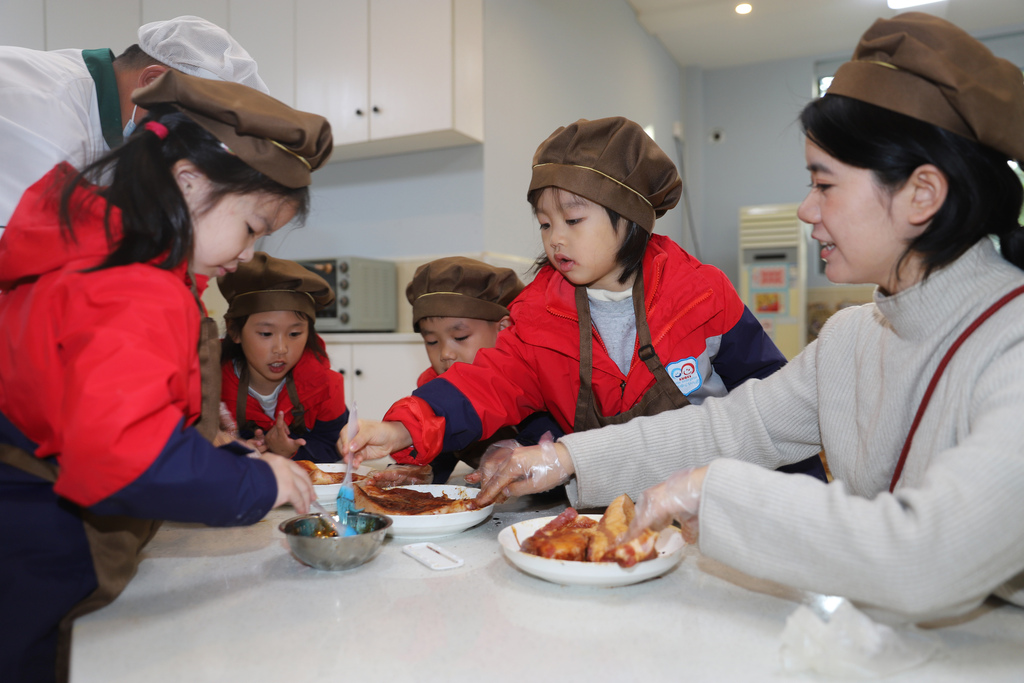 Children learn how to cure preserved pork at a kindergarten in Taizhou City, Jiangsu Province to mark the solar term of Major Snow. /VCG