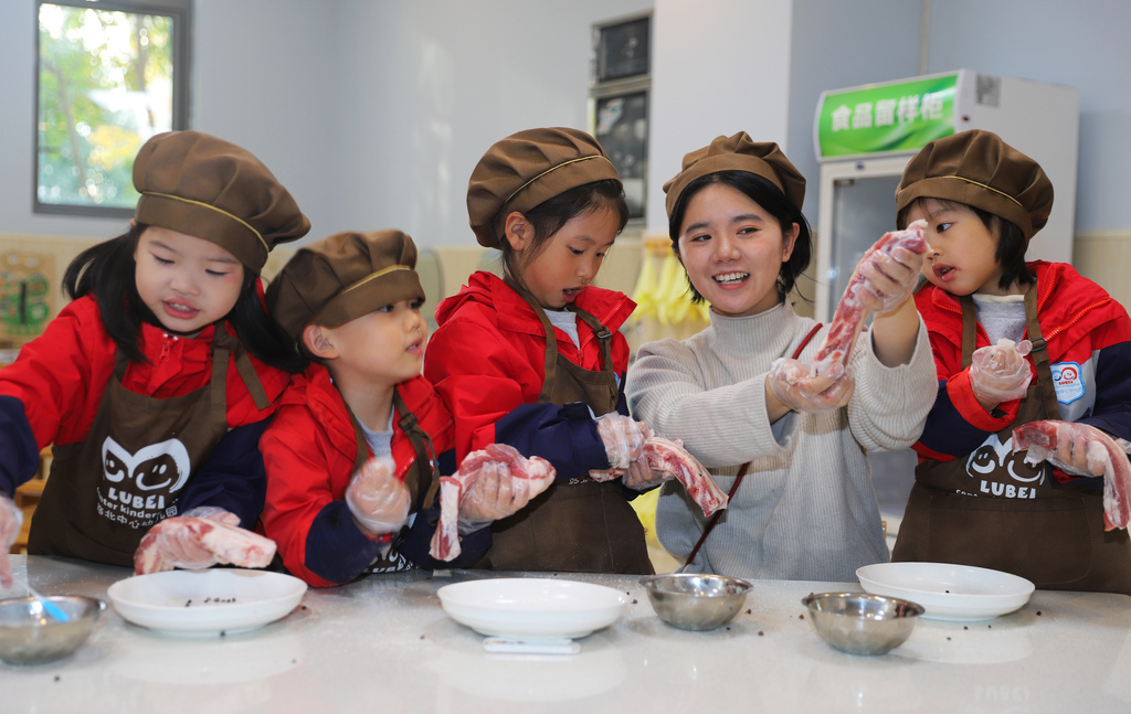 Children learn how to cure preserved pork at a kindergarten in Taizhou City, Jiangsu Province to mark the solar term of Major Snow. /VCG