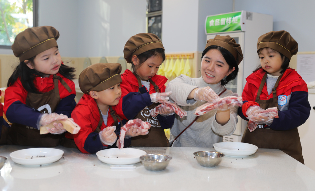 Children learn how to cure preserved pork at a kindergarten in Taizhou City, Jiangsu Province to mark the solar term of Major Snow. /VCG