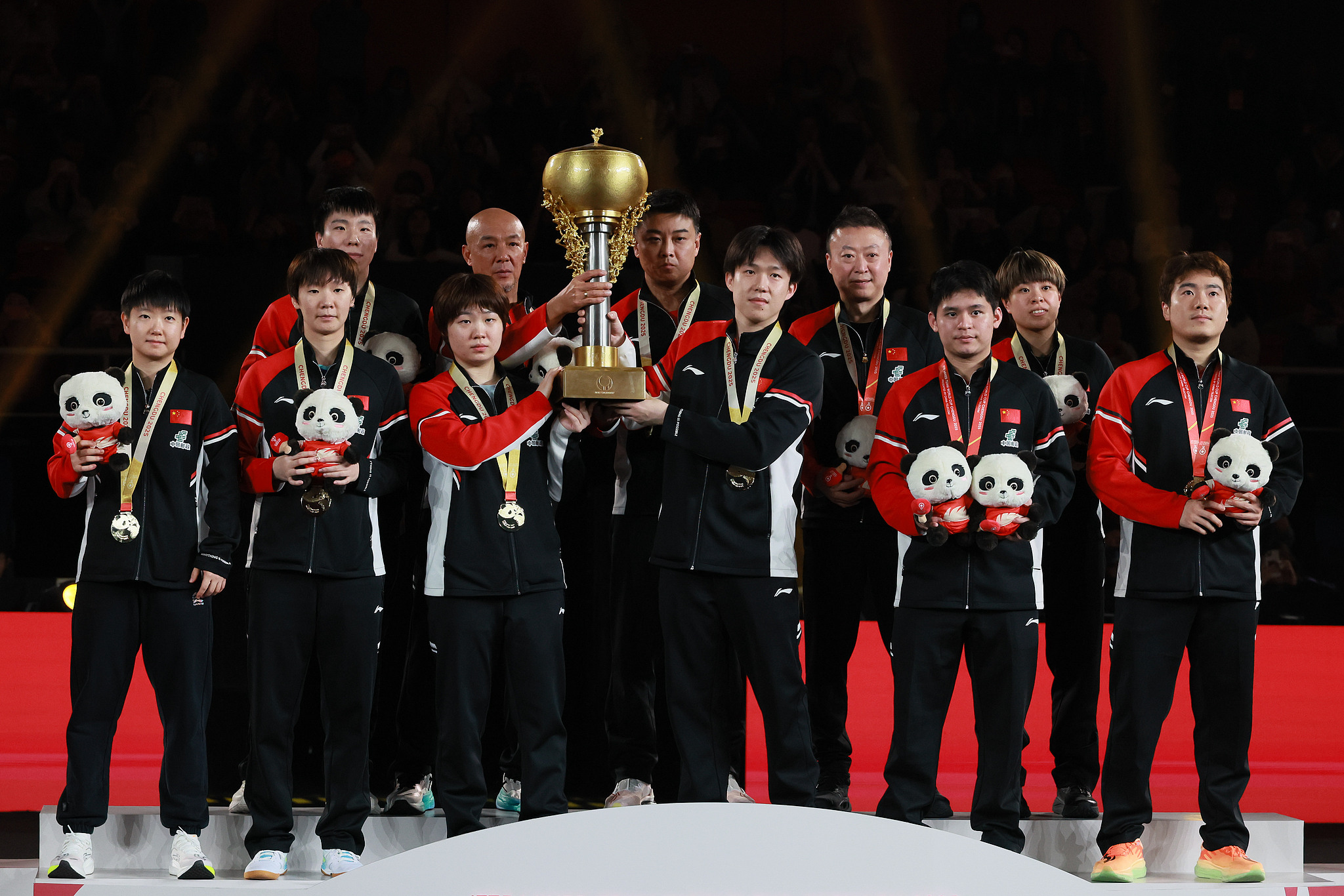 China's table tennis players and coaches celebrate with the trophy after defeating Japan to win the ITTF Mixed Team World Cup in Chengdu, China, December 7, 2025. /VCG