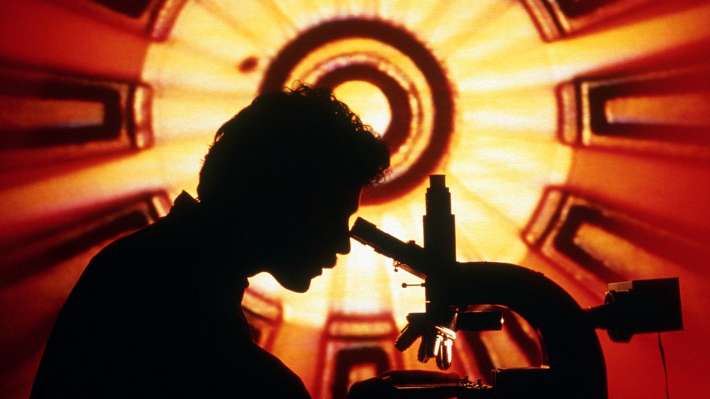 Silhouette of a scientist using microscope. /VCG